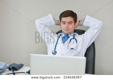 Smiling Doctor Posing In The Office, He Is Wearing A Stethoscope, Medical Staff On The Hospital Back