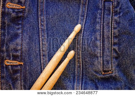 Two Drumsticks Lie On A Denim Jeans Textile