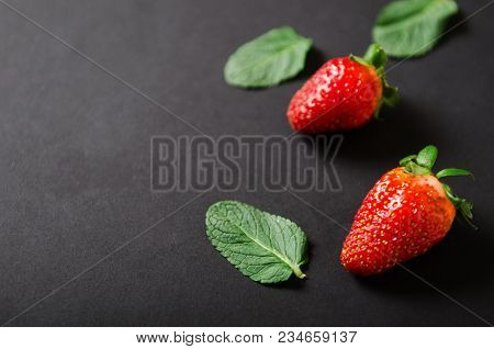 Strawberries And Mint. Red Ripe Berry With Mint Leaves On A Black Background. Copy Space