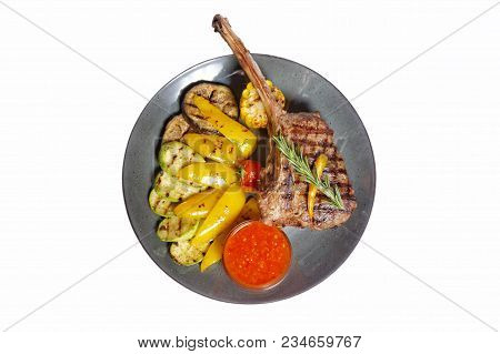 Fried Meat With Garnish Of Pepper, Zucchini, Tomato And Corn With Ajika Sauce Served On A Gray Plate