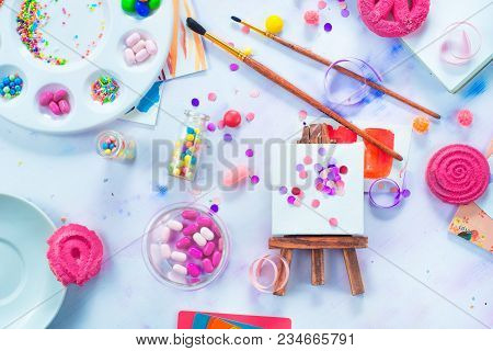 Tiny Easel With Confetti, Pink Macarons, Candies, Brushes And Watercolor Color Wheel. Sweettooth Art