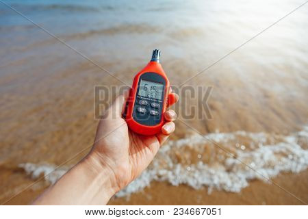 portable thermometer in hand measuring outdoor air temperature and humidity