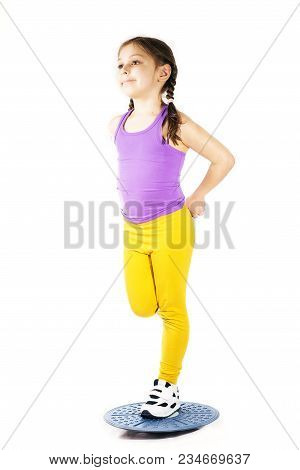 Little Caucasian Girl In On One Leg Position Staing On Balance Board. Photo On White Background