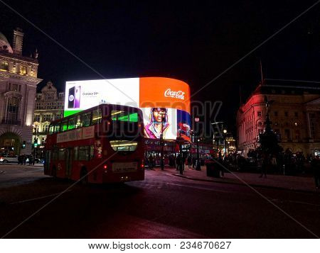 LONDON - APRIL 4, 2018: Tourists lit up at night by bright advertising illumination screens in Piccadilly Circus, Westminster, London, UK.