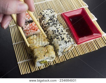 Sushi On A Black Background, Sticks, Hand