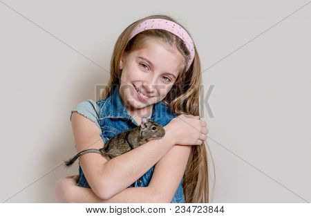 Smiling little girl holding a degu on her arms