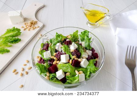 Salad Of Beetroot, Feta Cheese And Lettuce Leaves With Pine Nuts On White Wooden Background