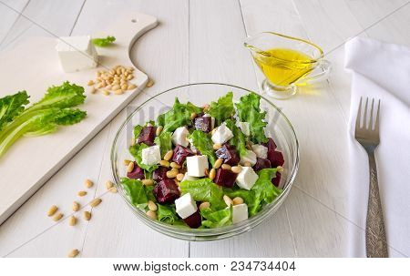 Salad Of Beetroot, Feta Cheese And Lettuce Leaves With Pine Nuts On White Wooden Background