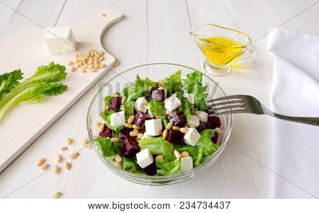 Salad Of Beetroot, Feta Cheese And Lettuce Leaves With Pine Nuts On White Wooden Background