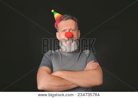 Mature man in funny disguise on dark background. April fool's day celebration