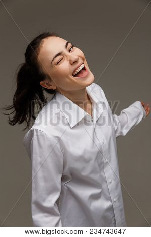 Beautiful Girl In A White Shirt Shows Emotions - Smile, Fun. On A Light Background.