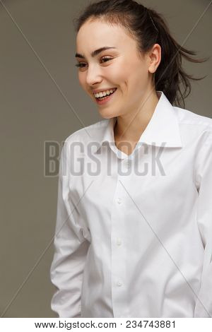 Beautiful Girl In A White Shirt Shows Emotions - Smile, Fun. On A Light Background.