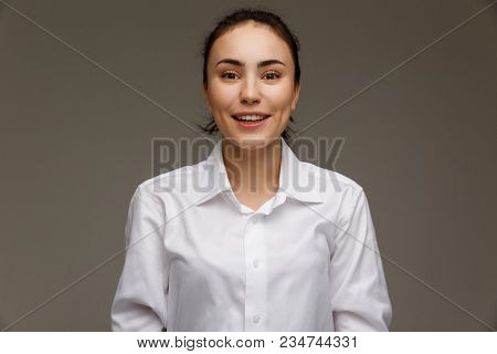 Beautiful Girl In A White Shirt Shows Emotions - Smile, Fun. On A Light Background.