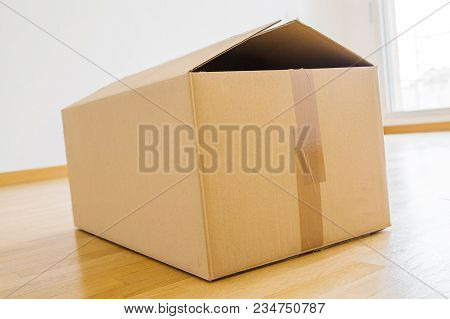 Single Cardboard Box On Wooden Floor For Shifting House From One Place To Another During Demotion