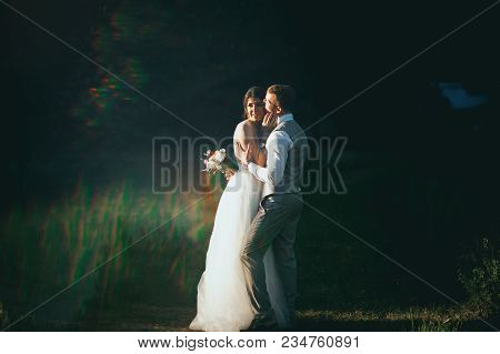 The Bride And Groom At Sunset On A Dark Background