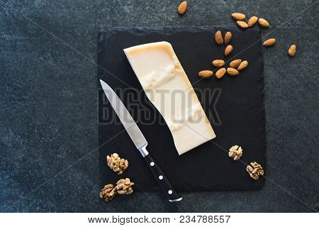 An Appetizing Solid Cheese On A Black Plate On A Gray Stone Background