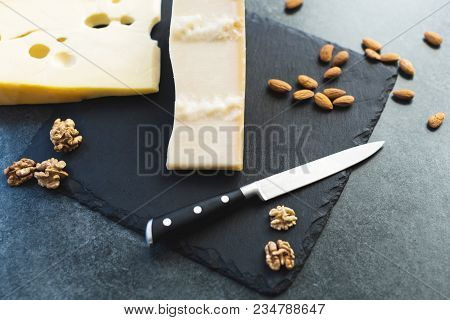 An Appetizing Solid Cheese On A Black Plate On A Gray Stone Background