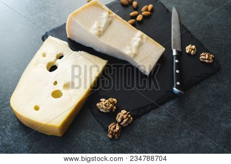 An Appetizing Solid Cheese On A Black Plate On A Gray Stone Background