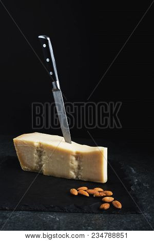 An Appetizing Solid Cheese On A Black Plate On A Gray Stone Background