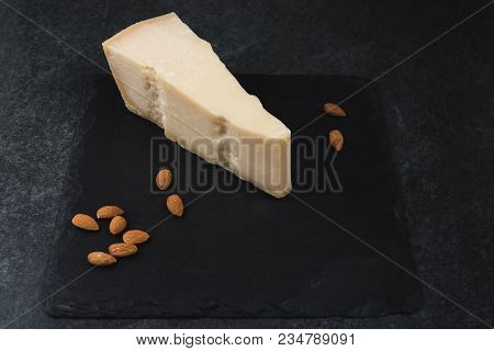 An Appetizing Solid Cheese On A Black Plate On A Gray Stone Background