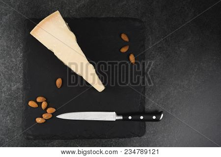 An Appetizing Solid Cheese On A Black Plate On A Gray Stone Background