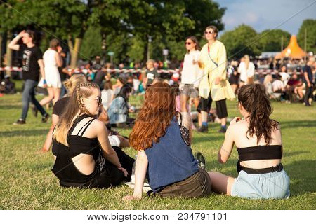 Roskilde, Denmark - June 29, 2016: People Sitting On Grass And Enjoying Sunshine And Concerts At Ros
