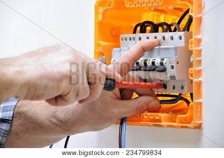 Electrician Technician Working On A Residential Electrical Panel, Fixing With A Screwdriver The Cabl