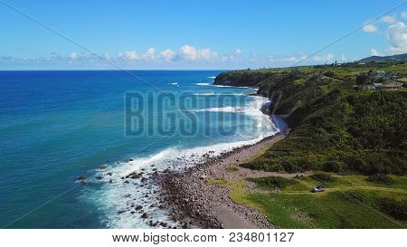 Aerial view of sea cliffs on St Kitts with vehicle parked along the shore.