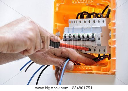 Electrician Technician Working On A Residential Electrical Panel, Fixing With A Screwdriver The Cabl