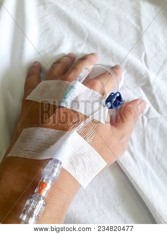 Patient Hand With The Tube Of Normal Saline Infusion On White Cloth Background
