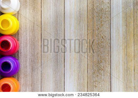 Row Of Colorful Paint Bottels On Rustic Wooden Background With Copy Space, Top View/arts And Crafts