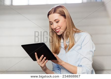 technology, business and corporate concept - happy woman or student with tablet pc computer at office stairs