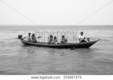 Boca De Valeria, Brazil - December 03, 2015: People Rowing In Boat On Brown Water Surface On Grey Sk