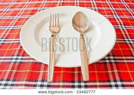 Forchetta e cucchiaio sul piatto bianco