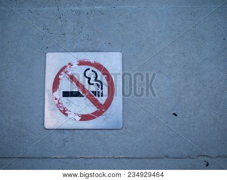 Worn-down No Smoking Sign Affixed To A Wall On A Building Outside