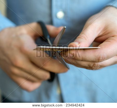Man Cutting Gold Credit Card With Scissors.