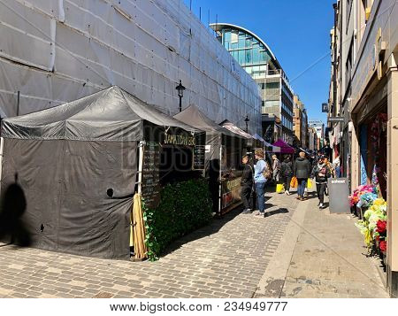 SOHO, LONDON - APRIL 5, 2018: Pedestrians at a market selling food, flowers, fruit and vegetables on Berwick Street in Soho, London, UK.