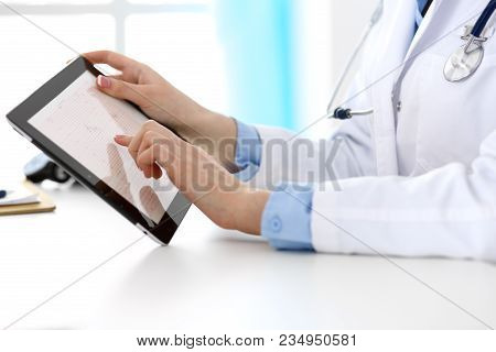 Closeup Of A Doctor Sitting At The Desk. Physician Pointing Into Tablet Pc. Medicine And Health Care