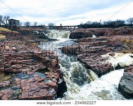 The Big Sioux River flows over rocks in Sioux Falls South Dakota with views of wildlife, ruins, park