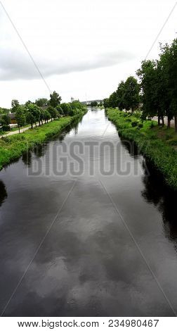 Alley Of Trees In The River Channel Canal In A Small Village.