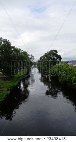 Alley Of Trees In The River Channel Canal In A Small Village.