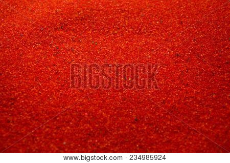 Texture Of A Colored Granular Sand Close Up. Red Grains