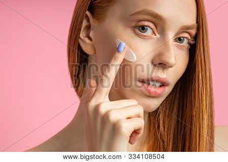 Closeup Cropped Shot Of Young Caucasian Redhead Woman Applying Foundation, Face Primer Or Moisturize