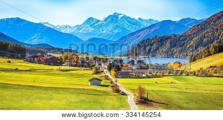 Magnificent Autumn View Of St.valentin Village And Haidersee (lago Della Muta) Lake With Ortler Peak