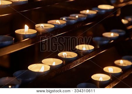 Rows of burning candles in a dim church