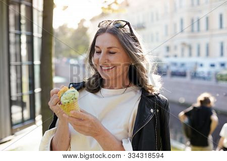 Cheerful beautiful mature European female in her fifty enjoying the nice summer weather outdoors, in