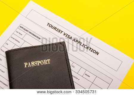 Travel Concept Showing A Passport And An Application Form For A Tourist Visa On A Yellow Background