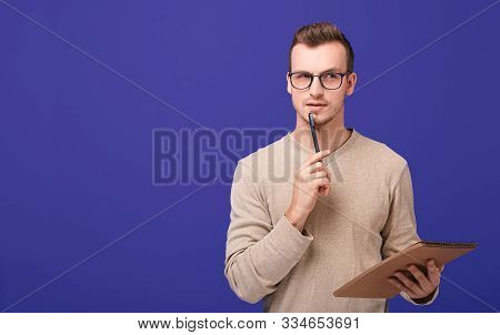 Young Confident Guy Redactor, A Professional In His Field. A Pensive Man Stands On A Purple Backgrou