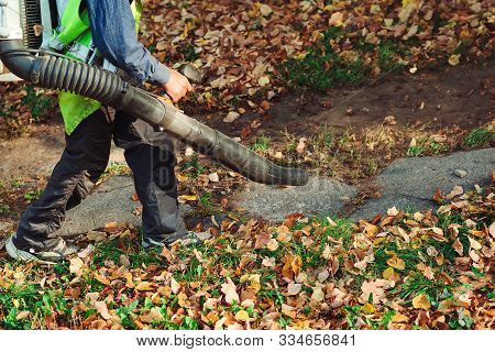 Man Using Leaf Blower For Cleaning Of The Road In The Park. Autumn Season. Park Cleaning Service