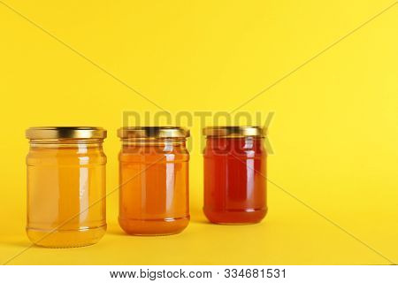Jars With Different Types Of Organic Honey On Yellow Background